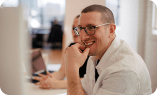 Smiling man sitting at computer rounded 400px